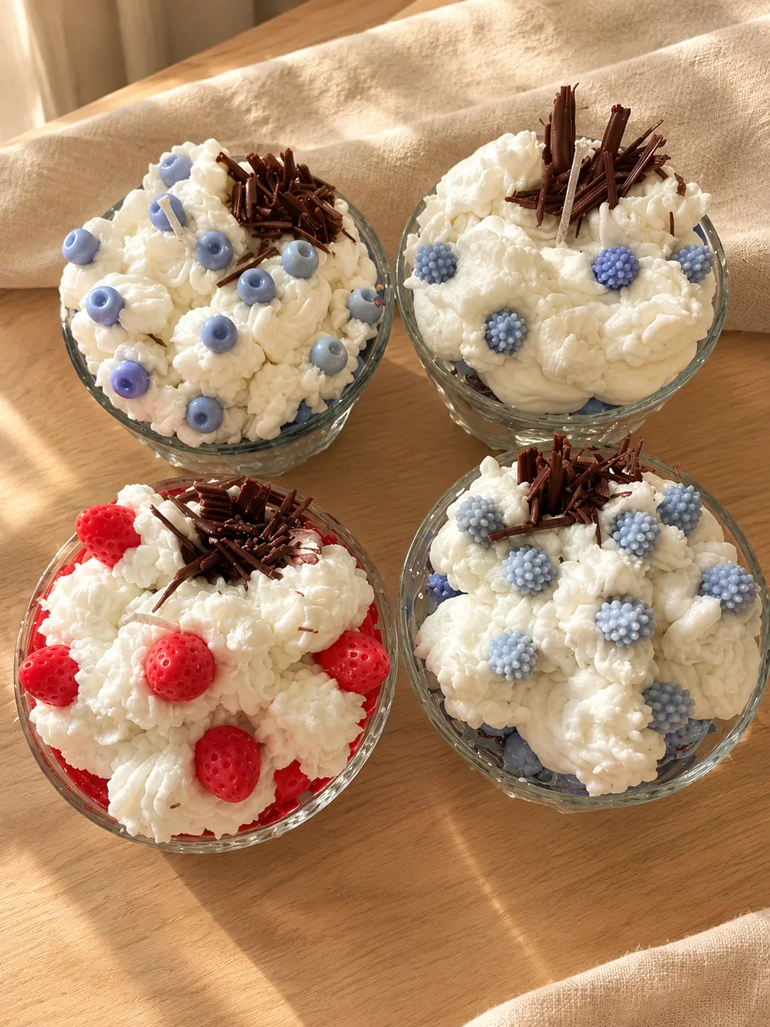 Four glass bowl candles topped with whipped wax, berries and chocolate curls