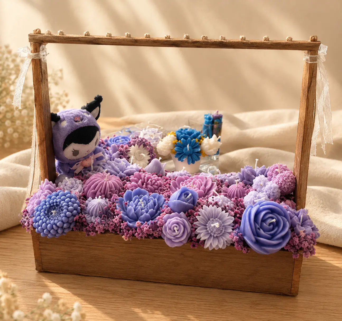 Wooden crate filled with purple and lilac wax flower candles and a purple plush character