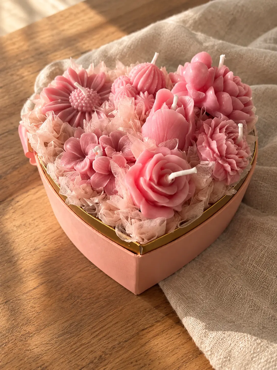 Pink heart-shaped box filled with pink wax rose, daisy and carnation candles