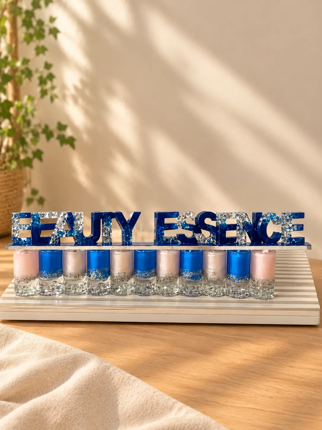 Blue and silver letters spelling BEAUTY ESSENCE above a row of pink, blue and white glass candles
