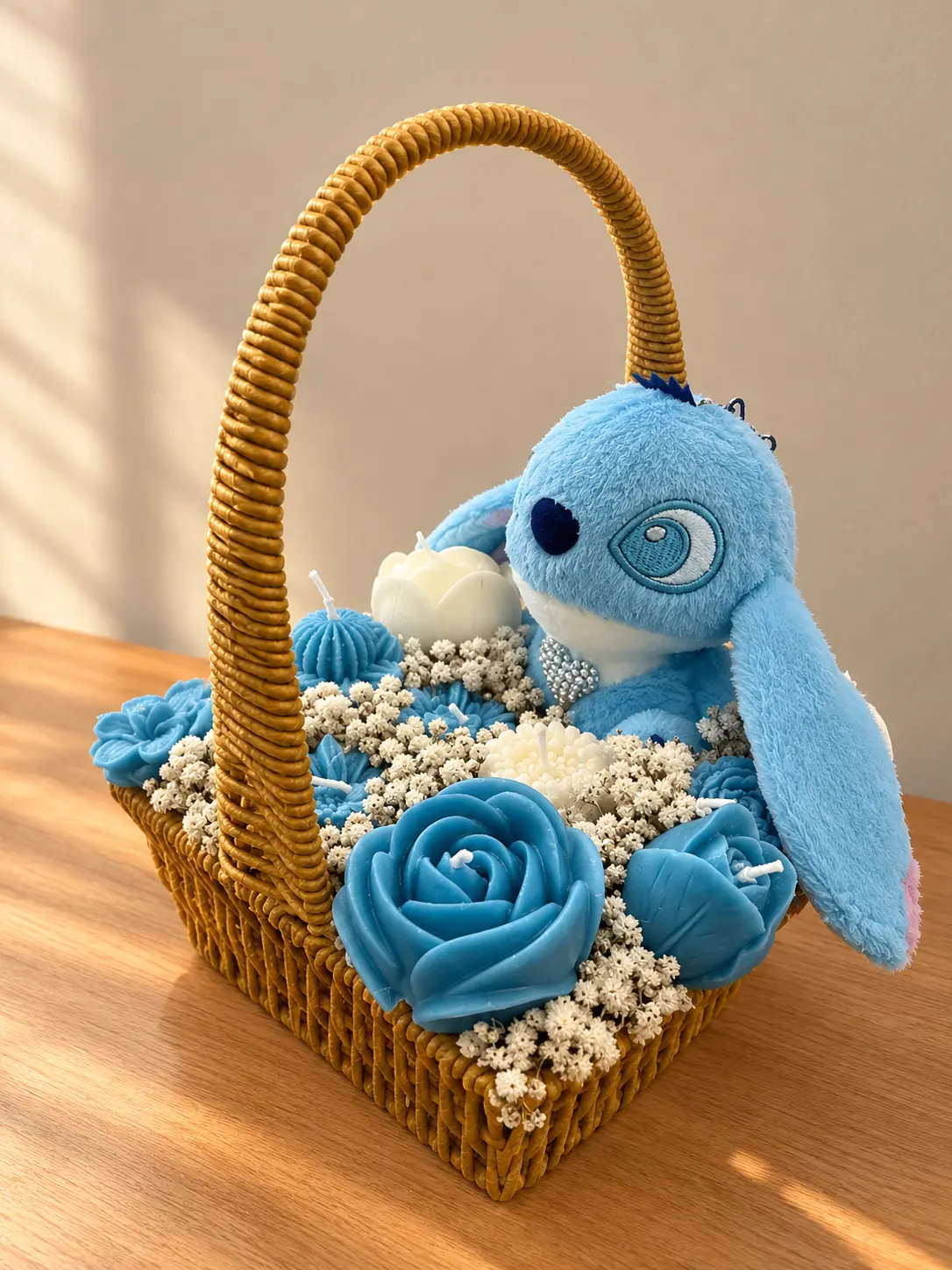 Woven basket of blue and white wax rose candles and baby's breath with a blue plush character